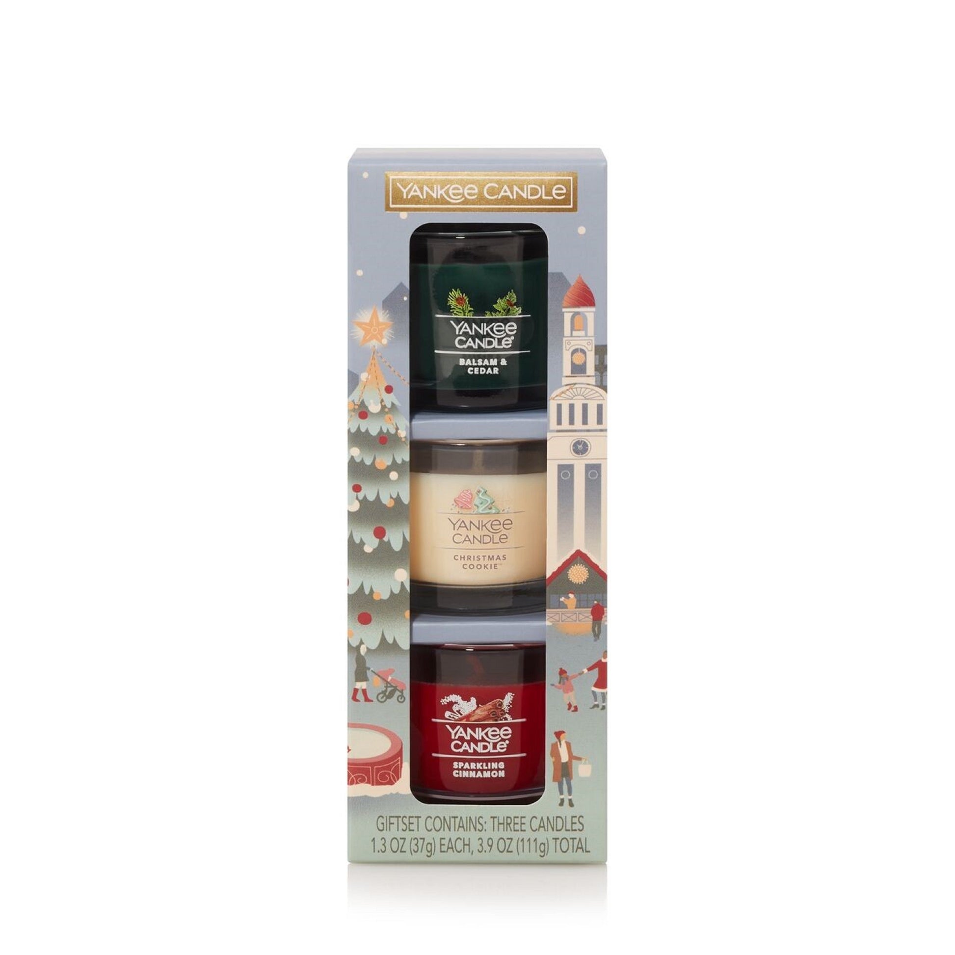 Set of three scented candles in a decorative holiday-themed box. text reads: gift set contains three candles.